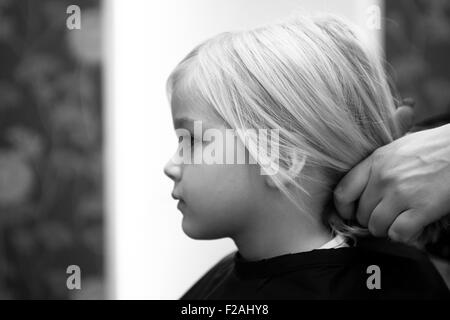 Coupe Coiffure féminine et le brossage du jeune enfant fille blonde cheveux dans le salon de coiffure Banque D'Images