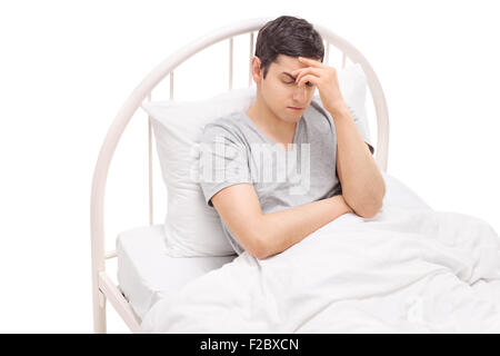 Jeune homme au lit et l'expérience d'une forte migraine isolé sur fond blanc Banque D'Images