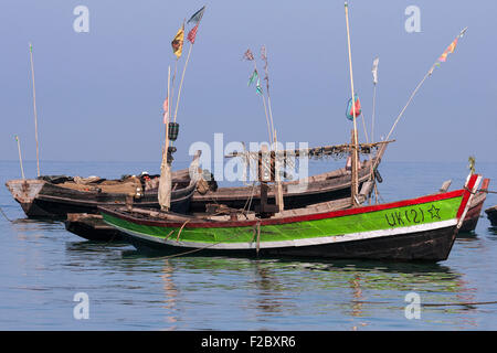 Bateaux de pêche colorés dans la mer au large de la plage du village de pêcheurs de Ngapali, Thandwe, l'État de Rakhine, au Myanmar Banque D'Images