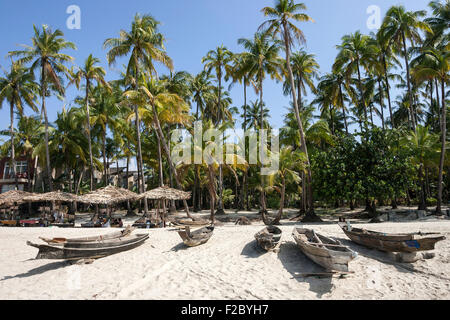 Plage avec parasols et de vieux bateaux de pêche sous les palmiers de la plage de Ngapali, à Thandwe, l'État de Rakhine, au Myanmar Banque D'Images