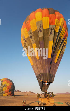 Gonflage pilote de ballon à air chaud avec deux brûleurs, la préparation pour le décollage au lever du soleil, deuxième derrière un ballon, Désert du Namib Banque D'Images