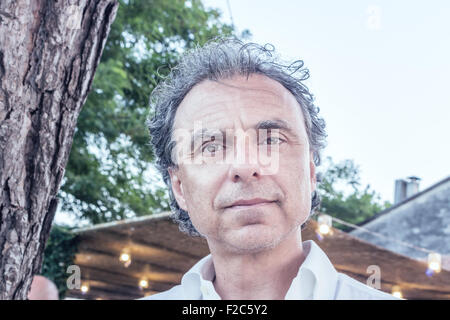 Homme d'âge moyen avec la peau douce et l'incroyable et des yeux verts perçants dans une chemise blanche en face d'un restaurant italien en plein air Banque D'Images