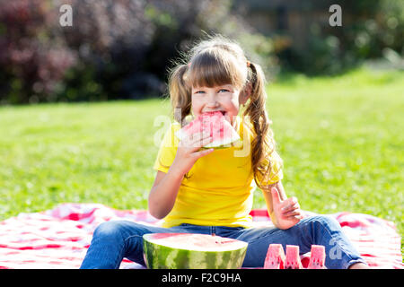 Cute little girl des pastèques sur l'herbe en été Banque D'Images