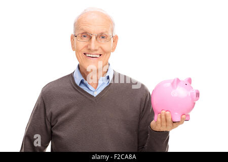 Cheerful senior gentleman holding a pink piggybank et regardant la caméra isolé sur fond blanc Banque D'Images