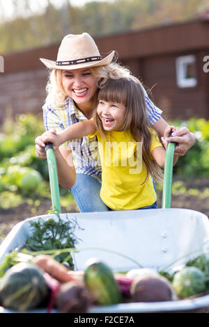 Mère et fille pushing Wheelbarrow avec Harvest Banque D'Images