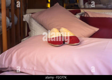 Chaussons femme rouge sur l'oreiller rose Banque D'Images