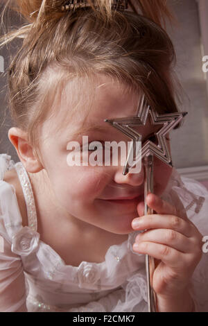 Portrait de jeune fille à la baguette en forme d'étoile de sourire et de regarder à travers la baguette sur l'appareil photo Banque D'Images