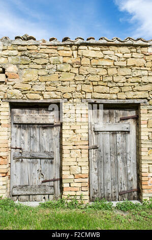 Ancienne grange en pierre dans le Marches Italie avec deux portes en bois patiné Banque D'Images