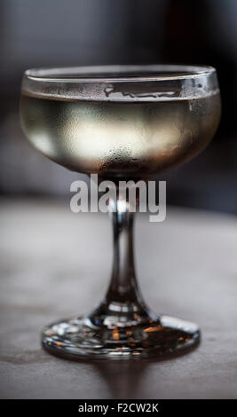 Cocktail unique sans glace en verre a pied à l'intérieur sombre. Banque D'Images