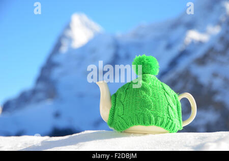 Pot de thé dans des étoffes de cap sur la neige Banque D'Images