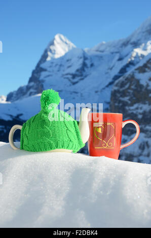 Pot de thé dans le cap et une tasse contre paysage alpin Banque D'Images