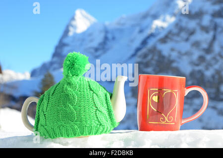 Pot de thé dans le cap et une tasse contre paysage alpin Banque D'Images