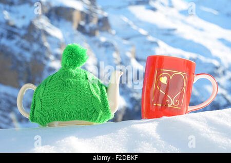 Pot de thé dans le cap et une tasse contre paysage alpin Banque D'Images