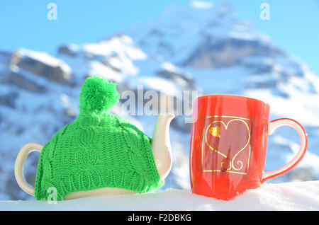 Pot de thé dans le cap et une tasse contre paysage alpin Banque D'Images