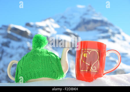 Pot de thé dans le cap et une tasse contre paysage alpin Banque D'Images