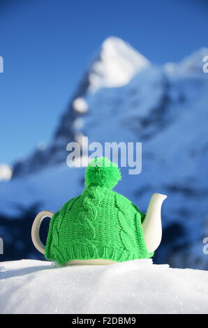 Pot de thé dans des étoffes de cap sur la neige Banque D'Images