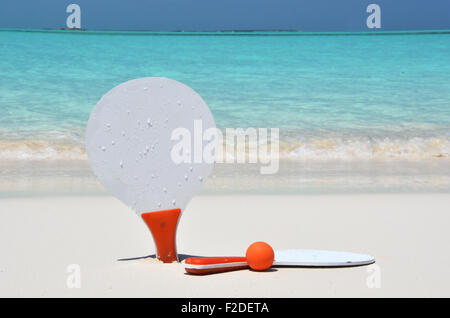 Deux raquettes et une balle sur la plage de sable Banque D'Images