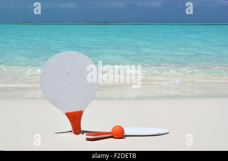 Deux raquettes et une balle sur la plage de sable Banque D'Images