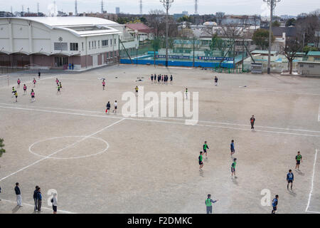 Saleté d'école avec des enfants qui jouent au football soccer de pov ci-dessus au centre de l'espace ouvert Banque D'Images