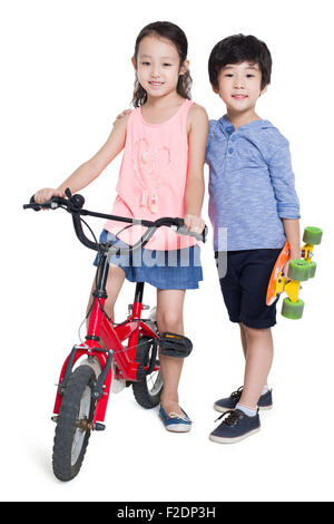 Little girl riding bike et boy holding a skateboard Banque D'Images