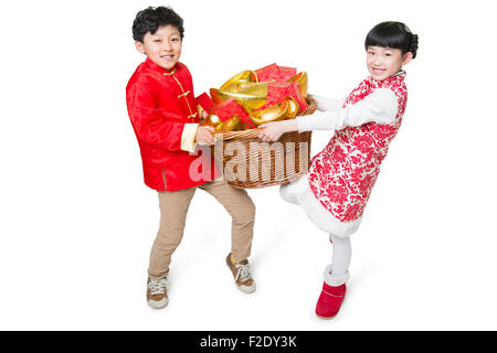 Heureux enfants portant des enveloppes rouges et la monnaie traditionnelle chinois yuanbao Banque D'Images