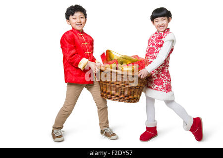 Heureux enfants portant des enveloppes rouges et la monnaie traditionnelle chinois yuanbao Banque D'Images