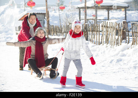 Famille heureuse de jouer avec traîneau dans la neige Banque D'Images