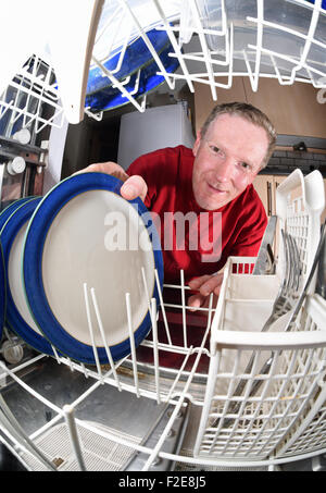 Nettoyer les assiettes de l'homme de lave-vaisselle dans la cuisine Banque D'Images