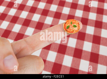 Plat à Pizza Margherita en miniature sur le doigt avec cirée avec damier rouge. Banque D'Images