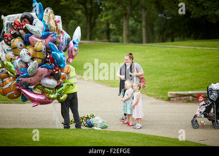 Heaton Park ballon vendeur dans le parc appartenant à Manchester City Council soeurs filles de parents en attente dans la pram enfant enfants novelt Banque D'Images