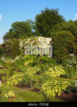 Chenies Manor ; vue portrait de jardin en contrebas dans le soleil l'après-midi avec des plantes vertes dans les frontières bien entretenus et ciel bleu Banque D'Images