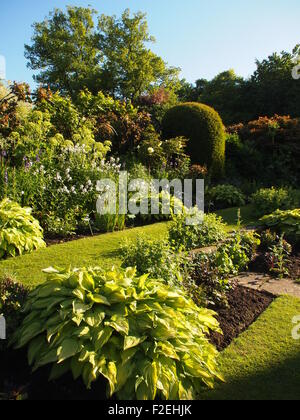 Chenies Manor ; vue portrait de jardin en contrebas dans le soleil l'après-midi avec des plantes vertes dans les frontières bien entretenus et ciel bleu Banque D'Images