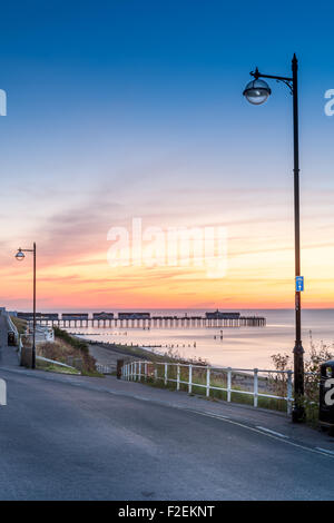 L'éclairage de la rue comme le soleil se lève derrière la jetée de la ville côtière de Suffolk Southwold. Banque D'Images