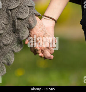 Les jeunes personnes âgées titulaires d'un côté, close-up les mains, la nature en arrière plan. Banque D'Images