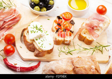 Bruschetta à la tomate, fromage et jambon on cutting board Banque D'Images