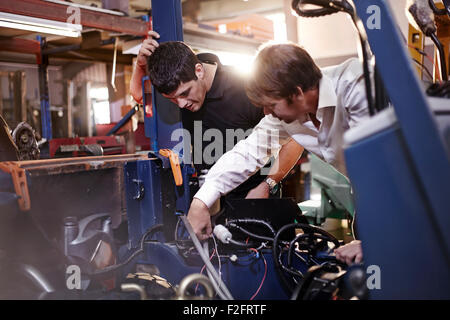 Mécaniciens travaillant sur voiture en atelier de réparation automobile Banque D'Images
