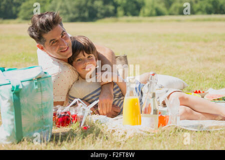 Portrait père affectueux et fils de détente sur couverture de pique-nique dans le champ ensoleillé Banque D'Images