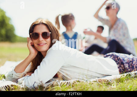 Portrait smiling woman laying on blanket in champ ensoleillé Banque D'Images