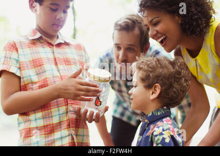 Family watching butterfly in jar Banque D'Images