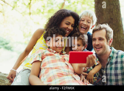 Multi-generation family en tenant avec selfies camera phone in woods Banque D'Images