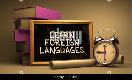 Apprendre les langues étrangères à la main sur tableau. Concept de temps. La composition avec tableau noir et pile de livres, Réveil et Banque D'Images