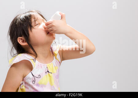 Fille asiatique malades médecine pour pulvérisation nasale dans le nez. Banque D'Images