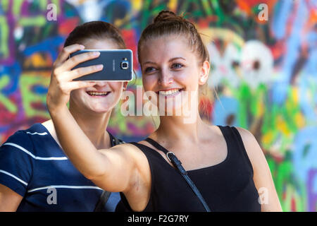 Deux femmes prennent un selfie devant John Lennon Wall Prague, République tchèque riant sur leur téléphone portable Banque D'Images