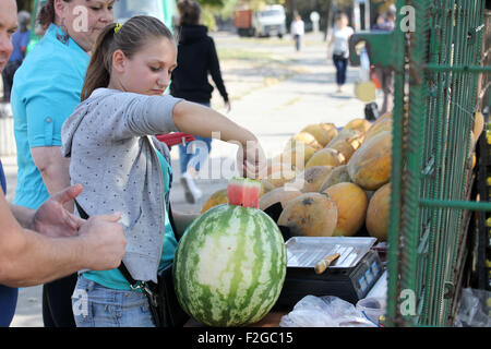 Les melons d'eau bon marché et les prix des melons saison en Ukraine, 2015. La jeune femme offre un melon d'eau coupé au goût Banque D'Images