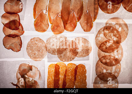 Tranches de salami divers translucide et prosciutto sur papier blanc deli retour allumé sur table lumineuse Banque D'Images