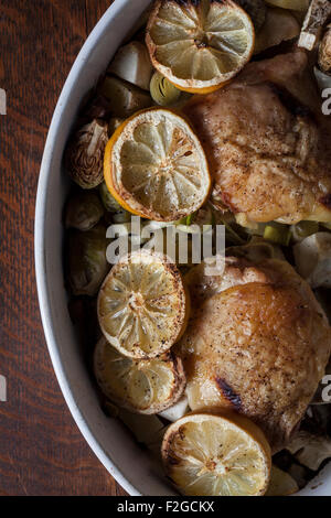 Vue aérienne de cuisses de poulet grillés dans un plat de cuisson ovale de citrons et les choux de bruxelles Banque D'Images