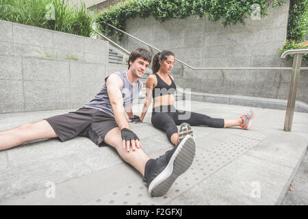 Couple de jeunes handsome young man and woman stretching sportif ainsi couché sur le sol, l'un donnant sur la gauche, l'autre à la recherche vers le bas - sportive, fitness, concept Banque D'Images