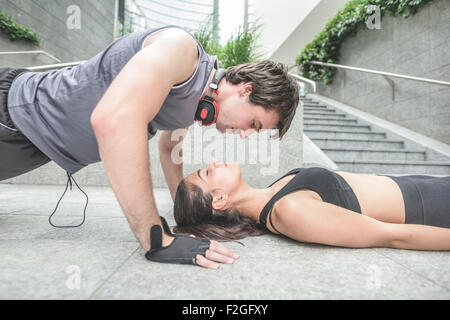 Couple de jeunes handsome young man and woman stretching sportif - il est en train de faire poussez se lève à sa petite amie qui est avec les yeux fermé - l'amour, le fitness, concept Banque D'Images