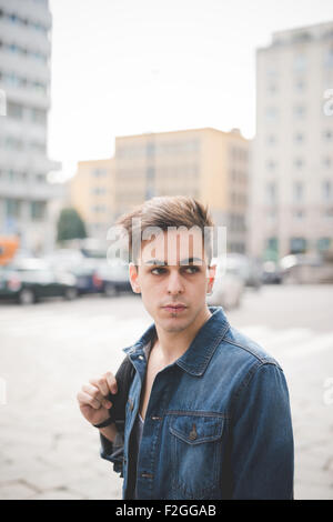 Demi-longueur de jeunes beau modèle sombre alternative homme marchant dans la rue à gauche avec labret piercing narine et centrale - la jeunesse, la rébellion, concept de diversité Banque D'Images