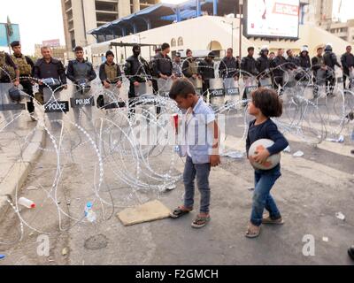 Bagdad, Iraq. 18 Sep, 2015. Deux enfants se tenir devant les forces de sécurité irakiennes dans une rue pendant une manifestation contre la corruption et une mauvaise qualité des services en ce qui concerne les coupures de courant et des pénuries d'eau, à la place Tahrir, dans le centre de Bagdad, Iraq, 18 Septembre, 2015. © Khalil Dawood/Xinhua/Alamy Live News Banque D'Images